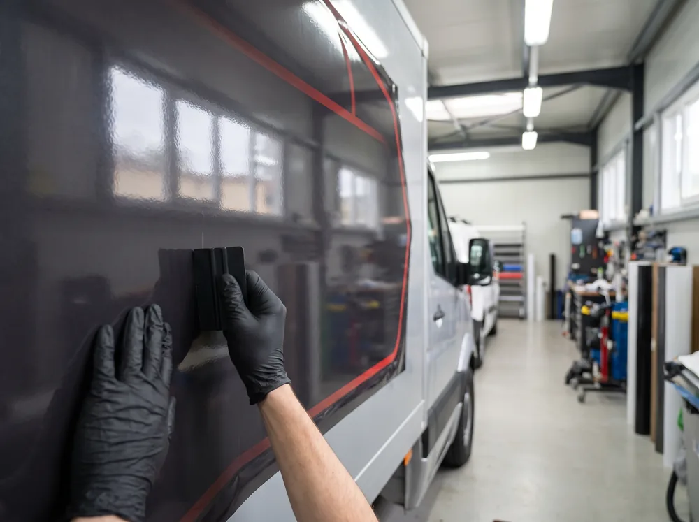 Installer squeegeeing vinyl onto a truck panel in a Winnipeg shop